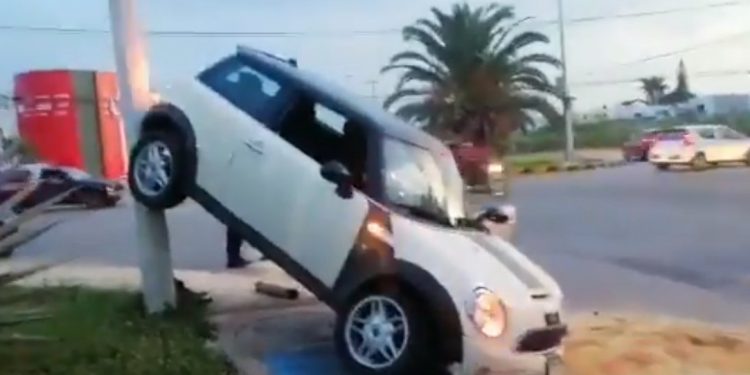 El exceso de velocidad, el piso mojado y las prisas, provocaron que una conductora perdiera el control de su Mini Couper y tras atravesar un camellón e invadir los carriles contrarios terminó “colgada” en un poste de luz